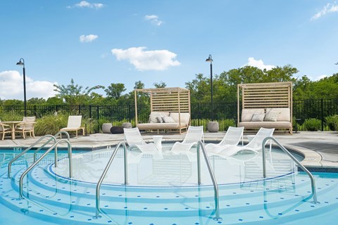 A round swimming pool with a metal railing and white lounge chairs.