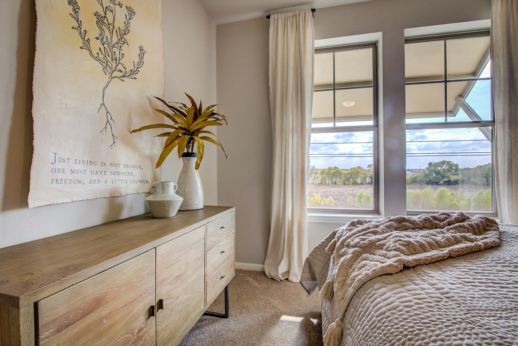 a bedroom with a large window and a dresser with a plant on it