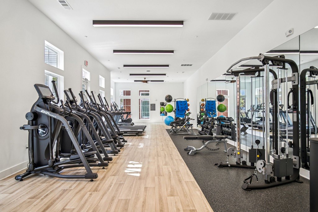 A gym with a variety of exercise equipment including treadmills, stationary bikes, and weight machines.