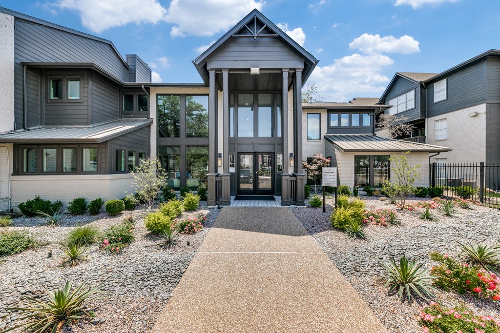 the front entrance of a house with a gravel pathway and plants