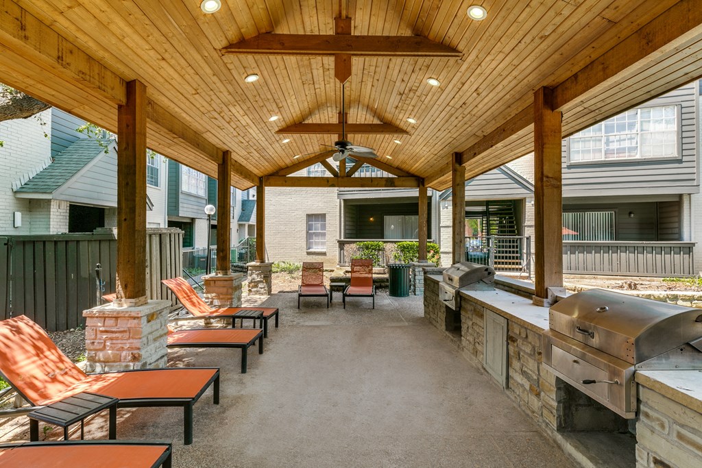 a covered patio with a grill and tables and chairs