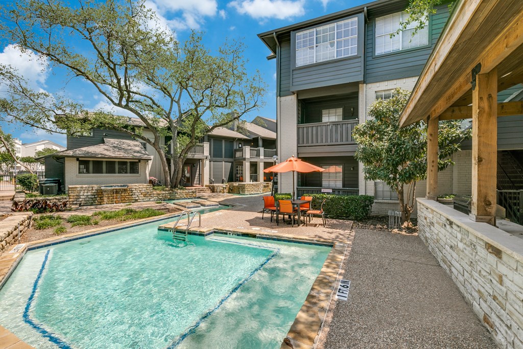a swimming pool with an umbrella in front of a house