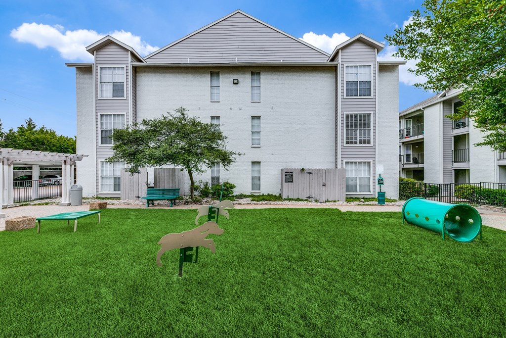 an apartment building with a yard with a dog statue and a ping pong table