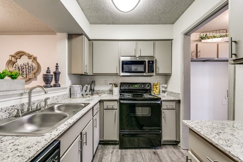 a kitchen with white cabinets and black appliances and granite counter tops