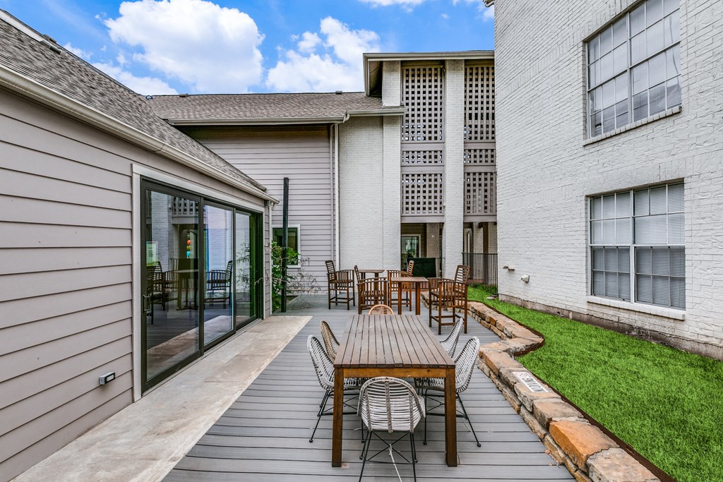 a patio with a wooden table and chairs in front of a building