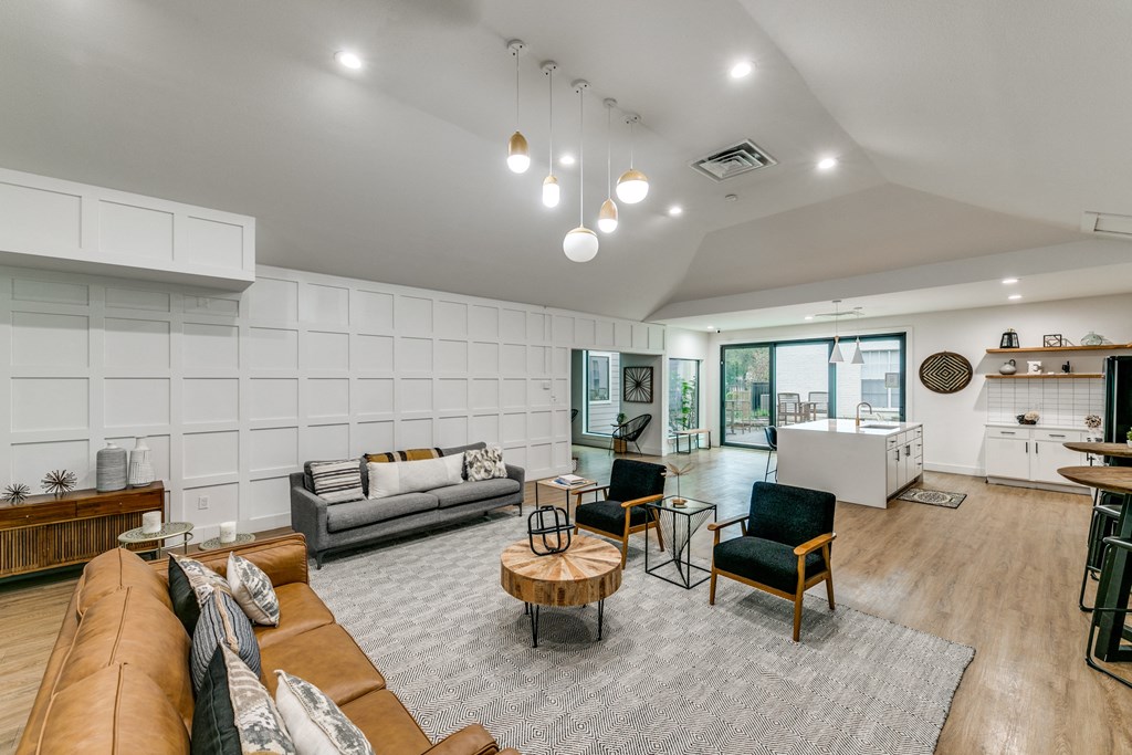 a living room with white walls and furniture and a kitchen