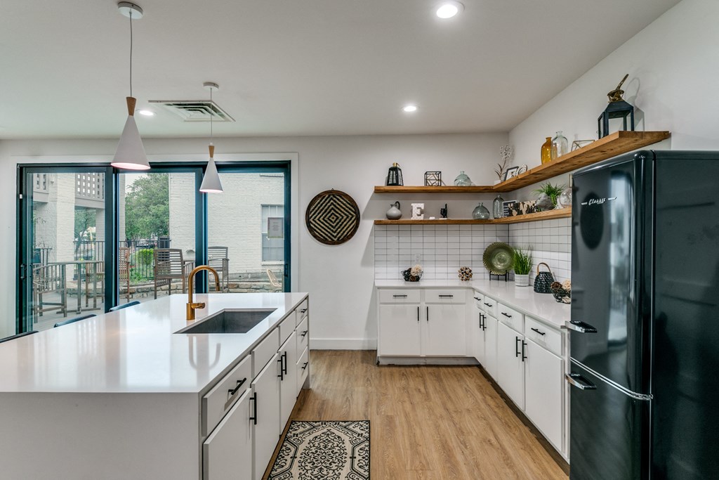 a kitchen with white cabinets and black appliances and a sliding glass door to a balcony