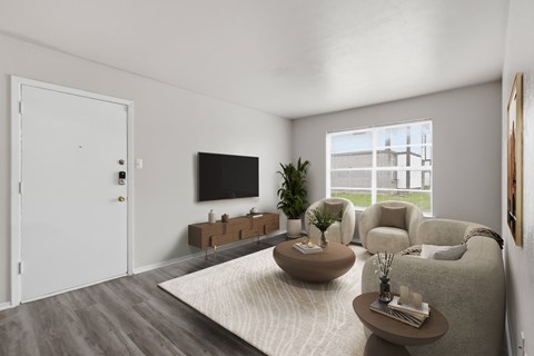 A living room with a grey sofa, a wooden coffee table, a flat screen TV, and a large window.
