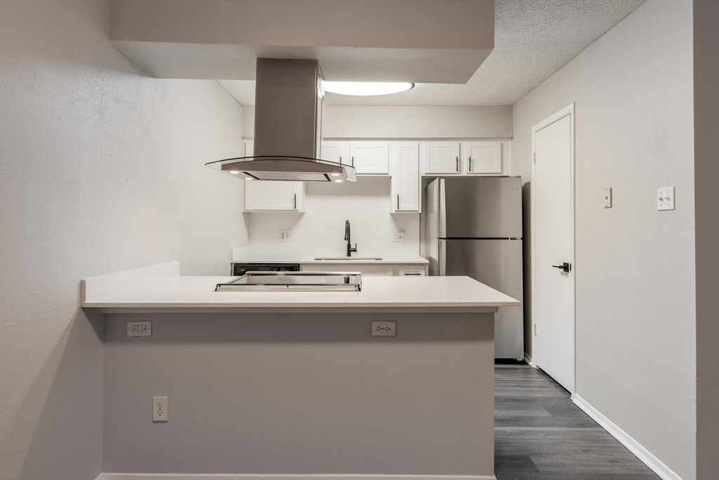 a kitchen with a white counter top and a refrigerator