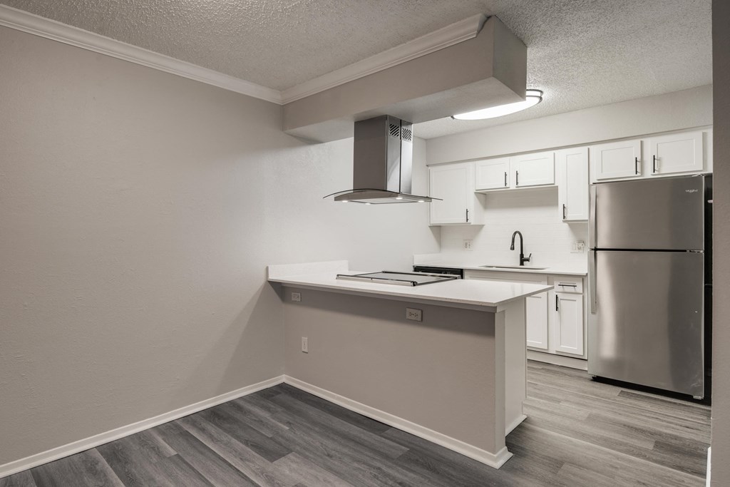 an empty kitchen with white cabinets and a stainless steel refrigerator