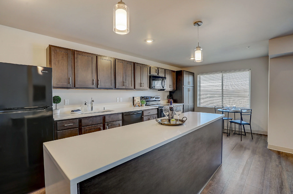 a kitchen with a large island and a stainless steel refrigerator