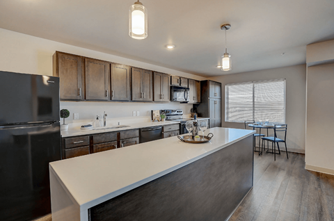 A modern kitchen with a black fridge and wooden cabinets.