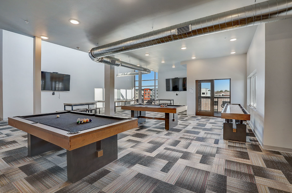 a game room with two pool tables and two televisions