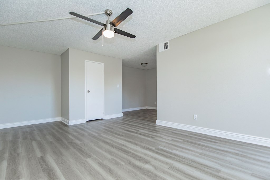 an empty living room with a ceiling fan