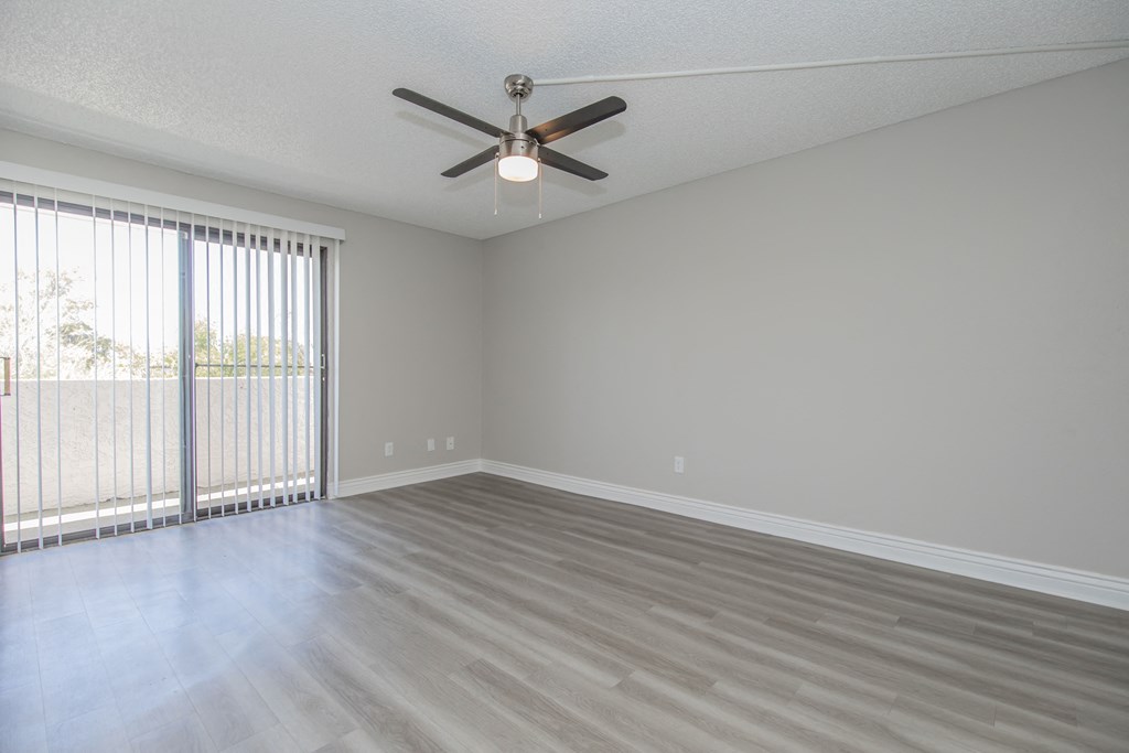 an empty bedroom with a ceiling fan and blinds