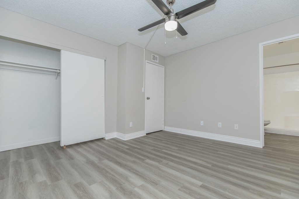 an empty bedroom with a ceiling fan and a closet