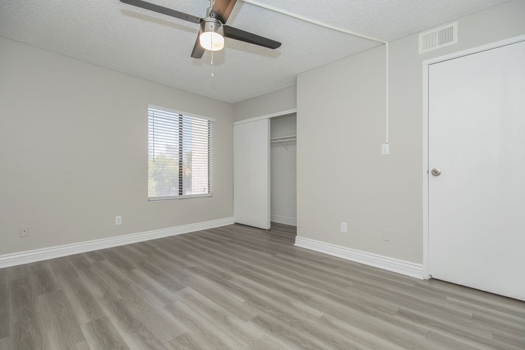 an empty bedroom with a ceiling fan and closet