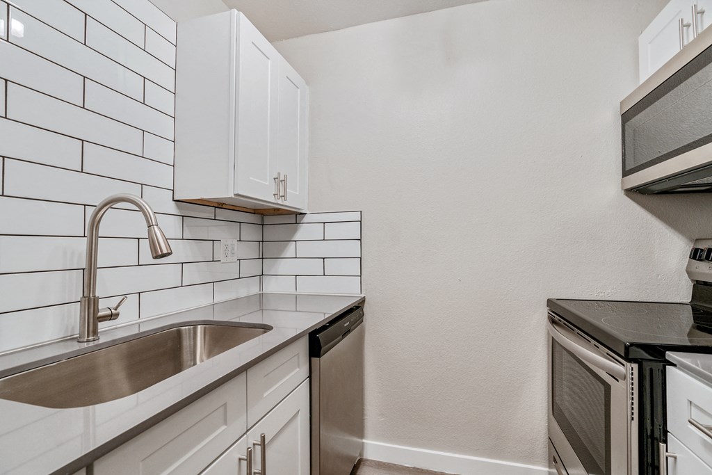 a kitchen with white cabinets and black countertops