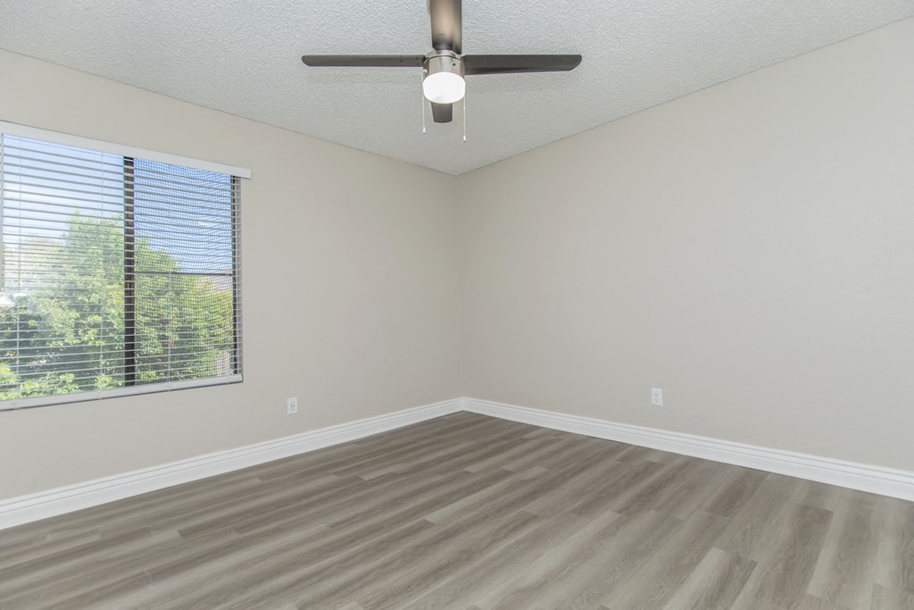 an empty bedroom with a ceiling fan and a window