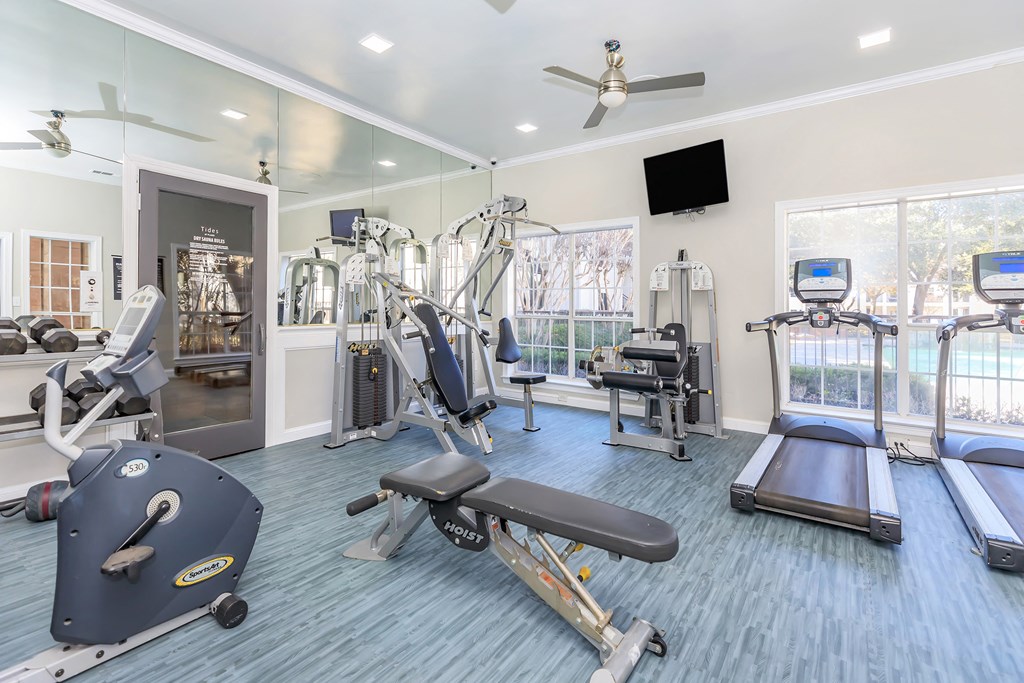a gym with cardio equipment and a flat screen tv