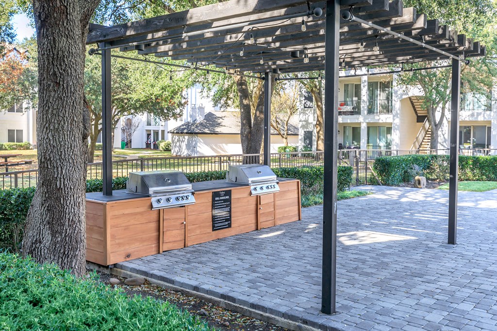 a picnic area with two bbq grills and a pergola