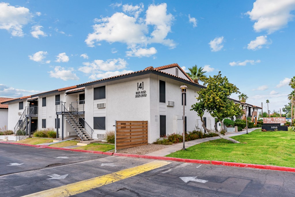 a white building with a brown roof and a street in front of it