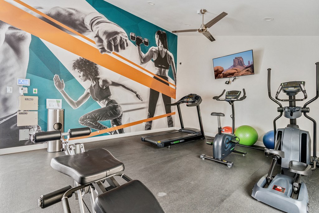 a gym with cardio equipment and a large mural on the wall