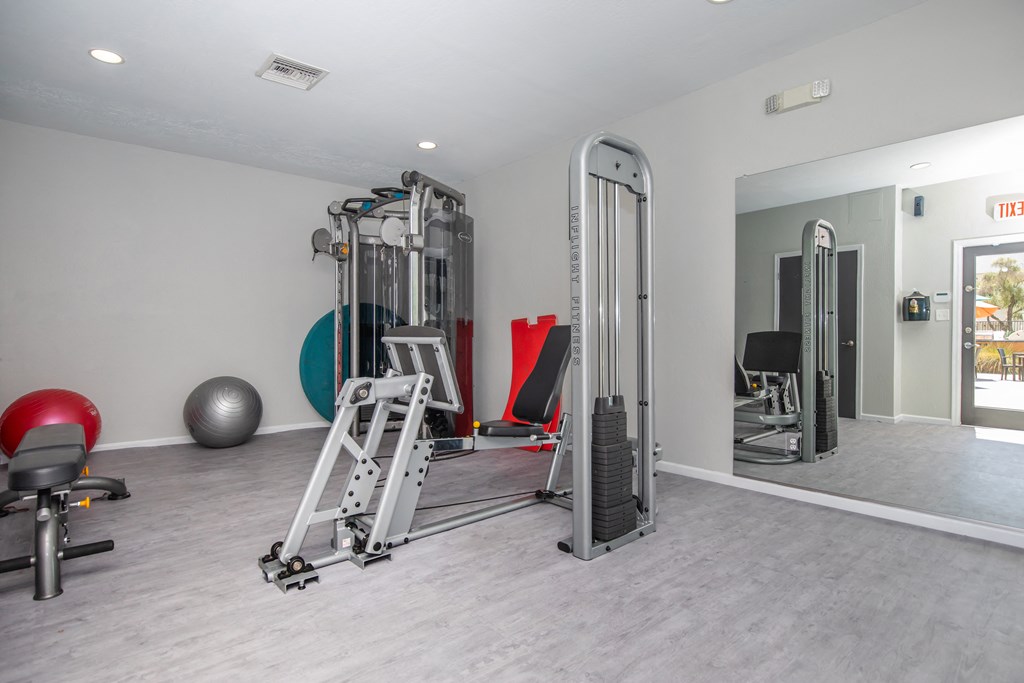 a gym with weights and cardio equipment at the whispering winds apartments in pearland, tx