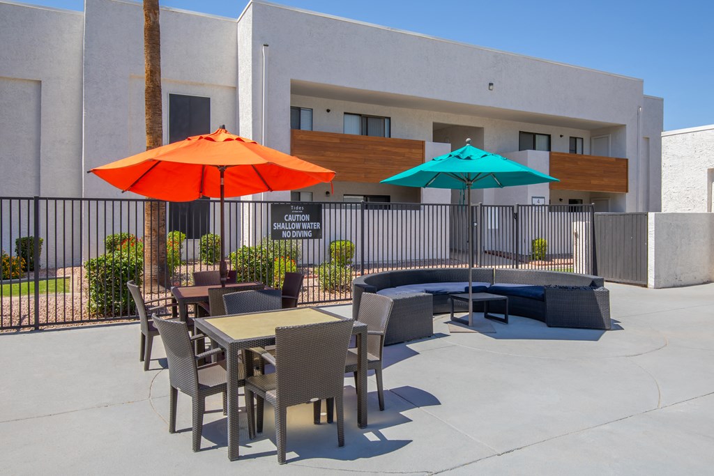 a patio with tables and umbrellas in front of a building