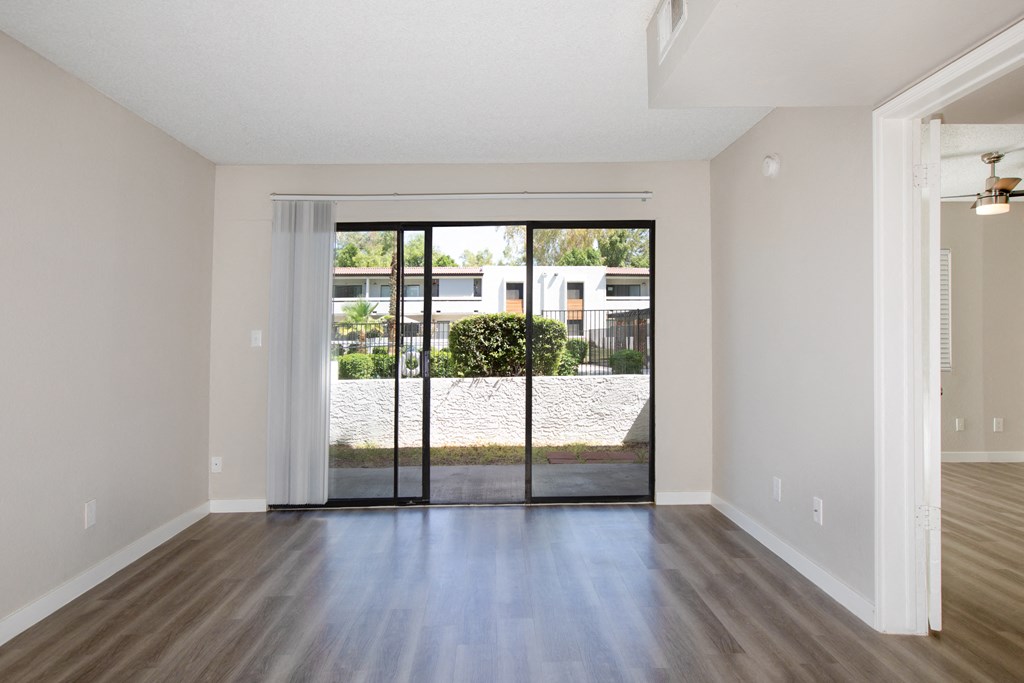 an empty living room with sliding glass doors to a yard