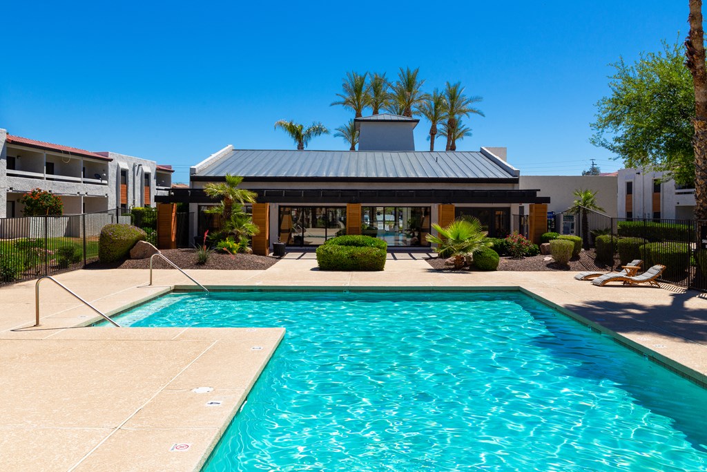 a swimming pool in front of a building with palm trees