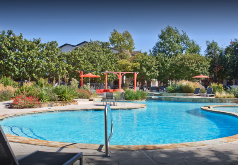 a swimming pool with a turquoise blue water and a patio area with umbrellas