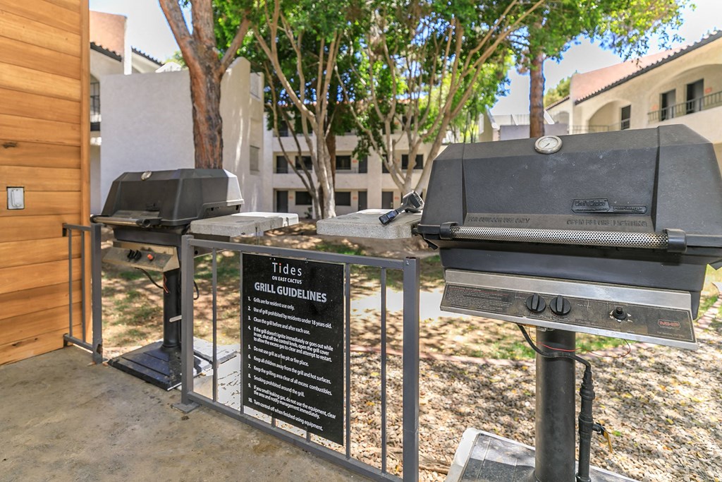 two bbq pits in front of a building with trees