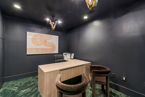 A room with a desk and chair and a painting on the wall.