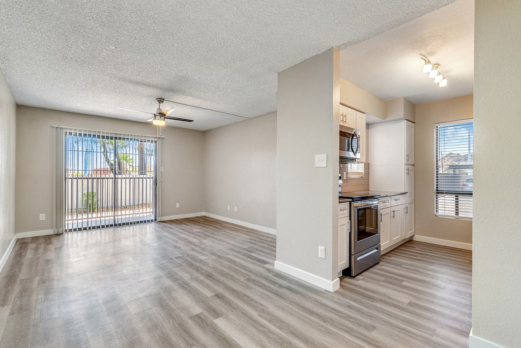 an empty living room with a kitchen and a balcony