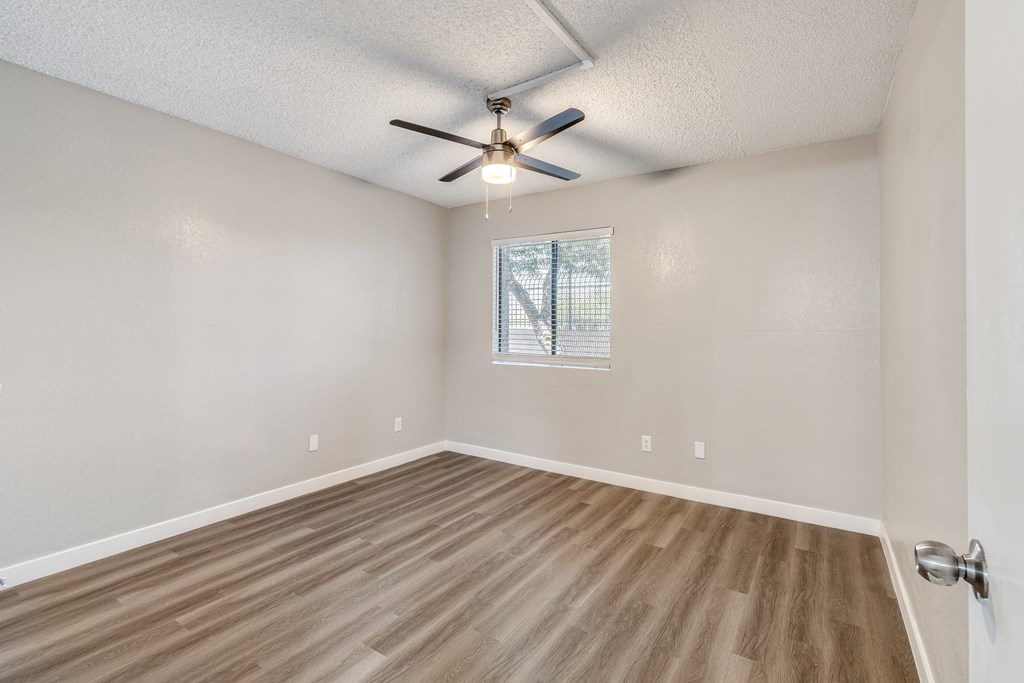 an empty bedroom with a ceiling fan and hardwood floors