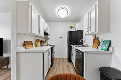 A kitchen with white cabinets and a black refrigerator.