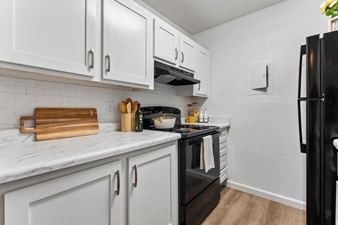 A kitchen with white cabinets and a black refrigerator.