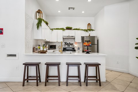A kitchen with white walls and a white counter top with a sign that says "Kitchen" on it.