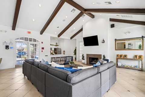 A grey couch in a spacious room with a fireplace and a flat screen TV mounted on the wall.