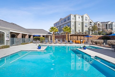 A large swimming pool in front of a building with a fence around it.