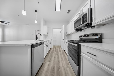 A modern kitchen with white cabinets and black appliances.