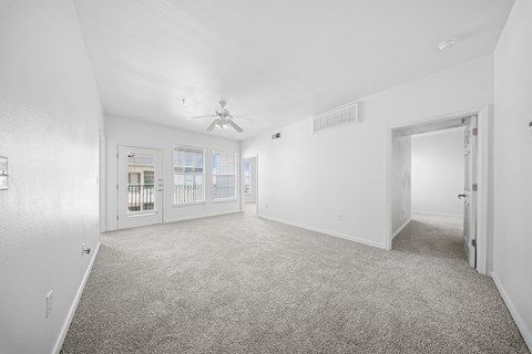A spacious room with a carpeted floor and a ceiling fan.