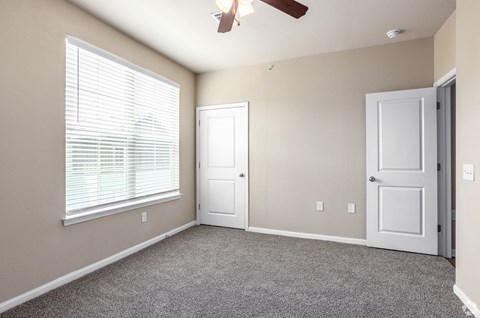 an empty living room with a window and a ceiling fan