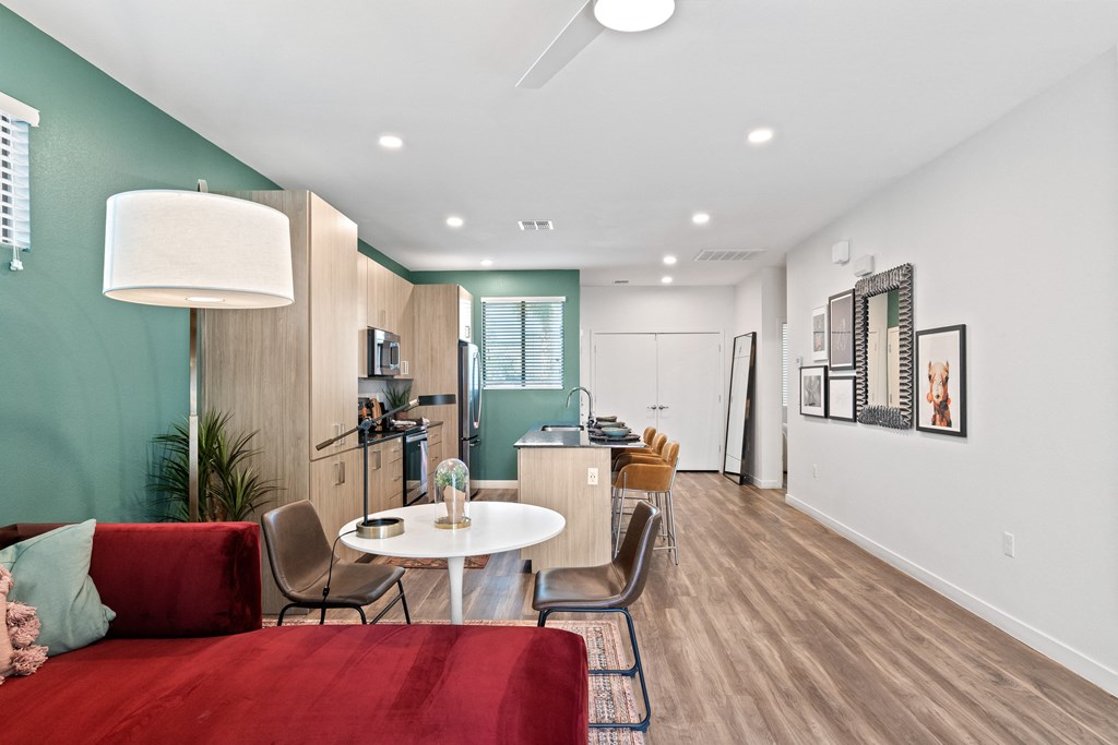 a living room with a red couch and a table and a kitchen