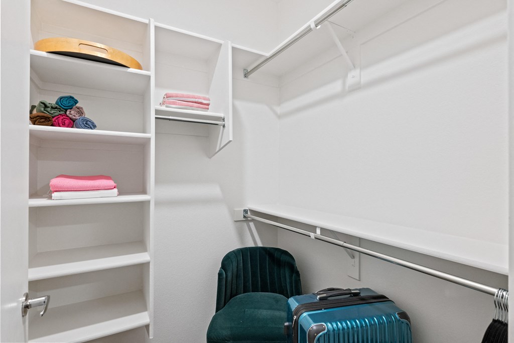 a walk in closet with luggage and chairs