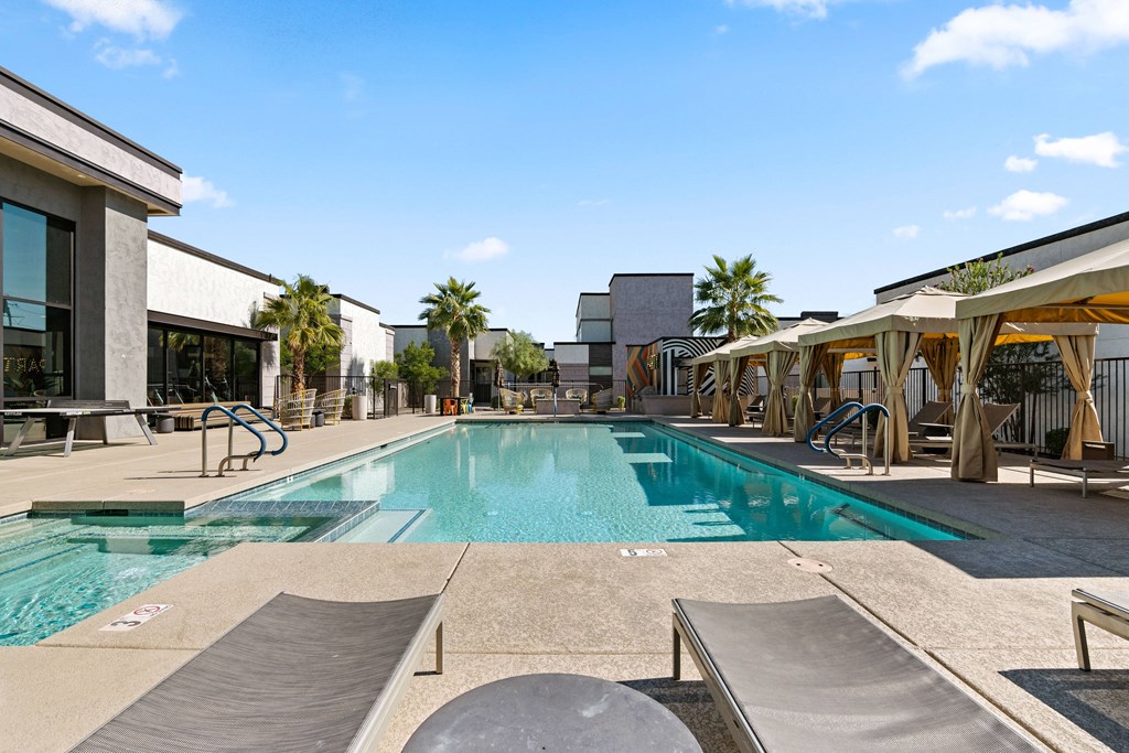 a swimming pool with tables and chairs next to a building