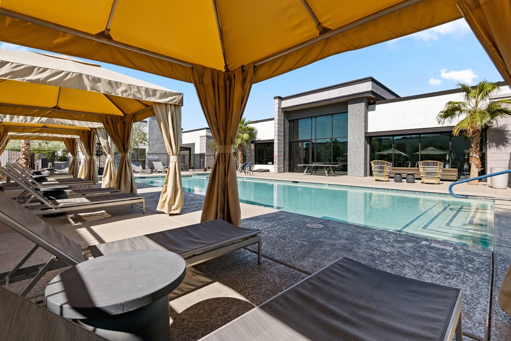a pool with lounge chairs and umbrellas next to a building