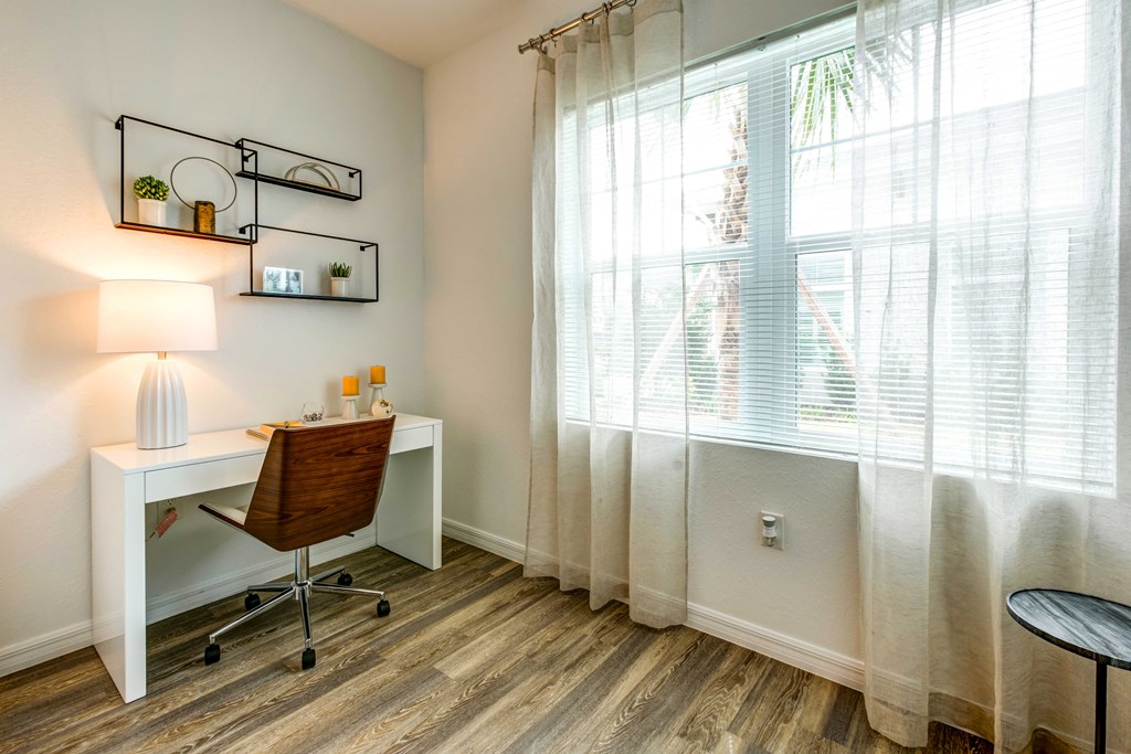 a home office with a large window and a wooden desk