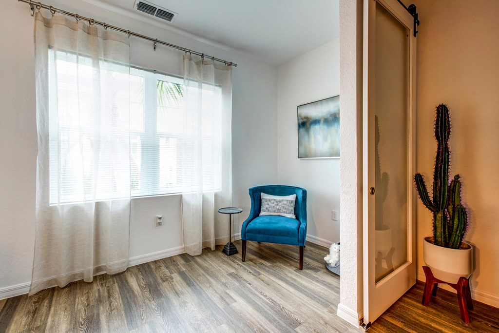 a living room with a blue chair and a cactus in the corner